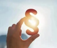 Eine Hand hält ein Paragrafen-Zeichen vor die Sonne, der BNE fordert die flexible Netznutzung von Windenergie, Photovoltaik und Batteriespeichern im EEG zu regeln.