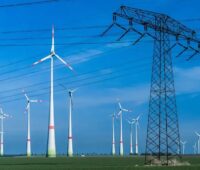 Windenergieanlagen hinter Strommast, das Netzpaket vom BMWE soll das Netzanschlussrecht für Windenergie einschränken.