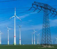 Windenergieanlage vor Strommast.