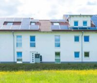 Ein Mehrfamilienhaus mit Photovoltaik-Anlage, das Standortfördergesetz ermöglicht Investitionen von offenen Immobilienfonds in Erneuerbare-Energien-Anlagen.