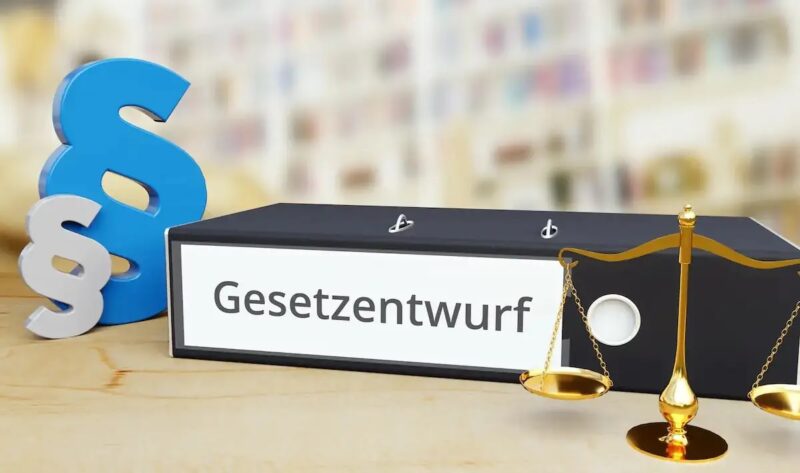 Ordner mit Aufschrift "Gesetzesentwurf", Paragrafenzeichen und Waage als Symbol für das geplante Netzpaket.