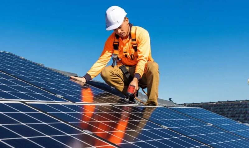 Ein Monteur auf dem Dach baut ein Photovoltaik-Modul ein, Enercity beteiligt sich an Photovoltaik-Installateur Hanovolt.