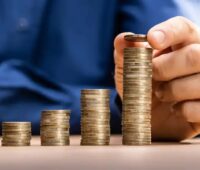 Ein Mensch stapelt Münzen, die Bürgerbeteiligung kann als Instrument der Eigenkapital- und Co-Finanzierung von Energiewende-Projekten von Stadtwerken dienen.