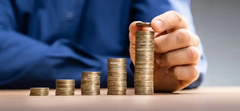 Ein Mensch stapelt Münzen, die Bürgerbeteiligung kann als Instrument der Eigenkapital- und Co-Finanzierung von Energiewende-Projekten von Stadtwerken dienen.