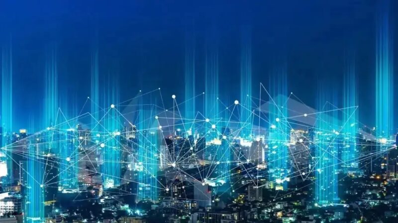 Eine Großstadt in der Nacht mit symbolischer Vernetzung durch helle Linien, vernetze Kleinbatteriespeicher in Mehrfamilienhäusern sollen Resilienz im Energiesystem erhöhen.