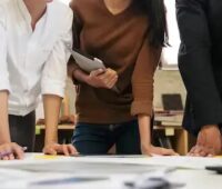Menschen stehen an einem Tisch, die Koordinierungsstelle Freiflächen-PV NRW begleitet Kommunen und Projektierer.
