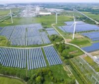 Luftbild von einem Photovoltaik-Solarpark und Windenergieanlagen, in Kombination mit Batteriespeichern steigt das Interesse an Stromabnahmeverträgen (Hybrid-PPA) solcher Anlagen in Deutschland.
