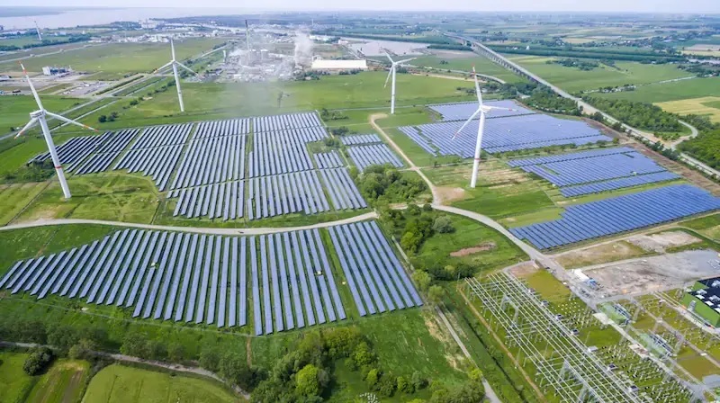 Luftbild von einem Photovoltaik-Solarpark und Windenergieanlagen, in Kombination mit Batteriespeichern steigt das Interesse an Stromabnahmeverträgen (Hybrid-PPA) solcher Anlagen in Deutschland.