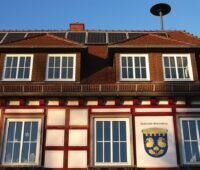 Die Fassade eines älteren Rathauses. Auf dem Dach eine Solarstrom-Anlage.