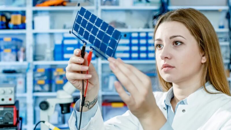 Frau in Laborkittel hält Solarzellen in die Luft, in aktiven, nur wenige Nanometer dünnen Schichten von neuen Solarzellen gelten die Gesetze der Quantenmechanik.