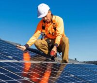 Ein Installateur auf dem Dach montiert Solarmodule, die Branchenvereinbarung soll die Sicherheit bei der Installation von Photovoltaik-Anlagen erhöhen.