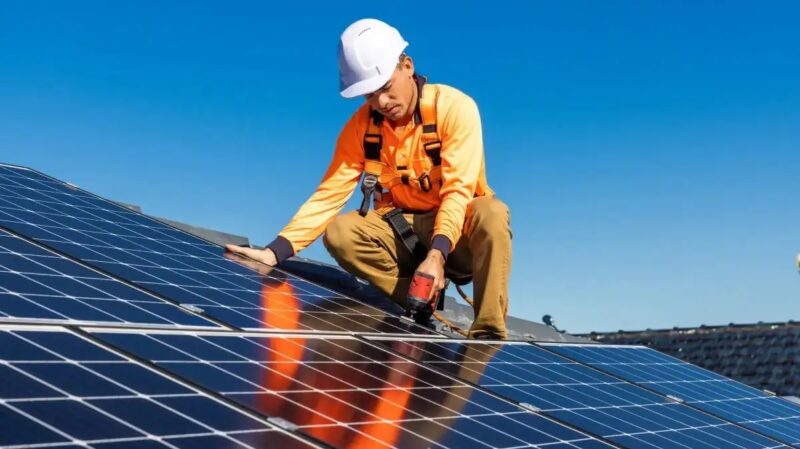 Ein Installateur auf dem Dach montiert Solarmodule, die Branchenvereinbarung soll die Sicherheit bei der Installation von Photovoltaik-Anlagen erhöhen.