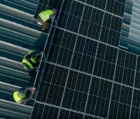 Drei Männer mit gelben Warnwesten bei Montage von Photovoltaik-Anlage