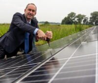 Bayerns Wirtschaftsminister Hubert Aiwanger bei der Montage eines Moduls an einer Solaranlage im Freien.