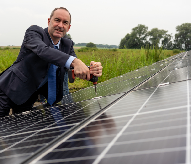 Bayerns Wirtschaftsminister Hubert Aiwanger bei der Montage eines Moduls an einer Solaranlage im Freien.