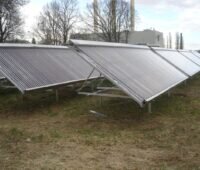 Solarkollektoren auf freiem Feld vor einer Heizzentrale