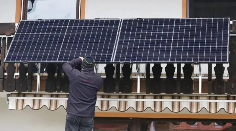 Im Bild ein Mann, der ein Balkonkraftwerk installiert, Vitapower ist ein Speichersystem für Balkonkraftwerke.