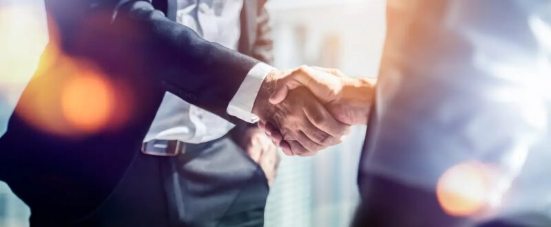 Das Bild zeigt im Anschnitt einen Handschlag zwischen zwei Männern in Anzügen als Symbolbild für eine Einigung.