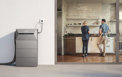 Zu sehen ist ein ein modulare Speicher von Anker Solix auf einer Terasse, der an einer Steckdose angeschlossen ist.