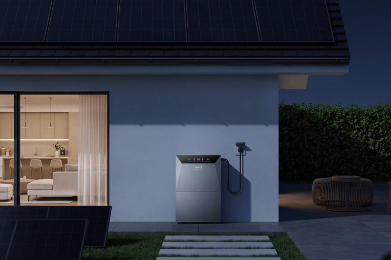 Zu sehen ist die neue Solarbank 4 Pro vor einer Hauswand bei Nacht. Links von dem Batteriespeicher steht auf dem Rasen eine PV-Balkon-Anlage.