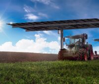 Im Bild das Agri-PV-System von Anywhere Solar mit zweiachsiger Nachführung, darunter fahren Trecker durch.