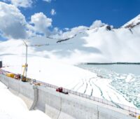 Bauarbeiten an einer Staumauer umgeben von Schnee.