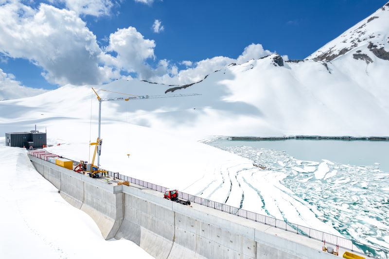 Bauarbeiten an einer Staumauer umgeben von Schnee.