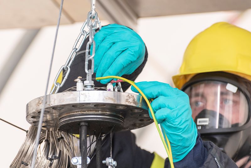 Ein Arbeiter ,it Schutzkleidung testet eine Lithium-Ionen-Batterie