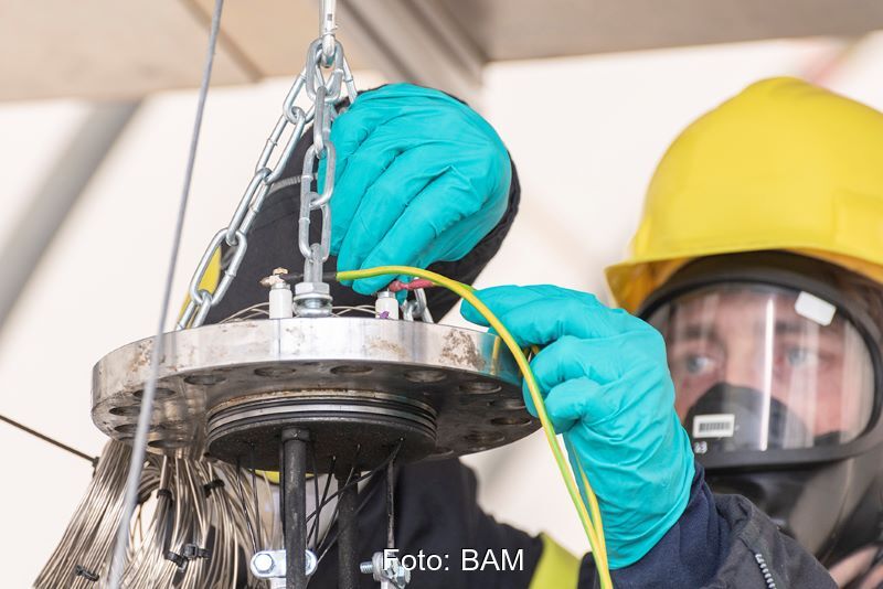 Ein Arbeiter ,it Schutzkleidung testet eine Lithium-Ionen-Batterie