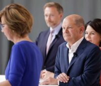 Zu sehen sind Olaf Scholz, Annalena Baerbock und Christian Linder beim BDEW-Talk zur Bundestagswahl. Im Vordergrund BDEW-Präsidentin Wolff, die ein ressortübergreifendes Klimaschutzministerium fordert.