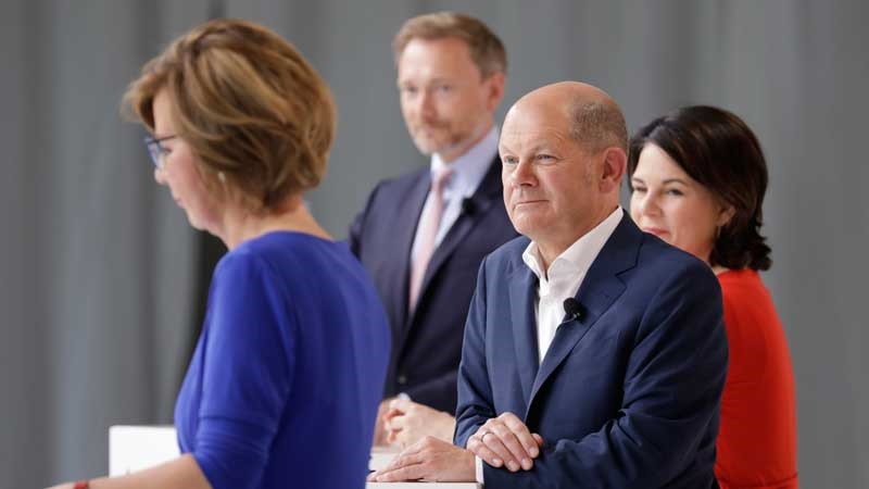 Zu sehen sind Olaf Scholz, Annalena Baerbock und Christian Linder beim BDEW-Talk zur Bundestagswahl. Im Vordergrund BDEW-Präsidentin Wolff, die ein ressortübergreifendes Klimaschutzministerium fordert.