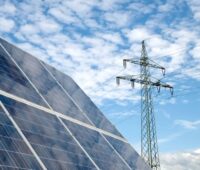 Im Bild Photovoltaik-Module und ein Strommast als Symbol für die Diskussion um die Differenzverträge (Contracts for Difference) in der EU.