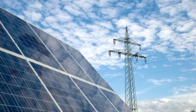 Im Bild Photovoltaik-Module und ein Strommast als Symbol für die Diskussion um die Differenzverträge (Contracts for Difference) in der EU.