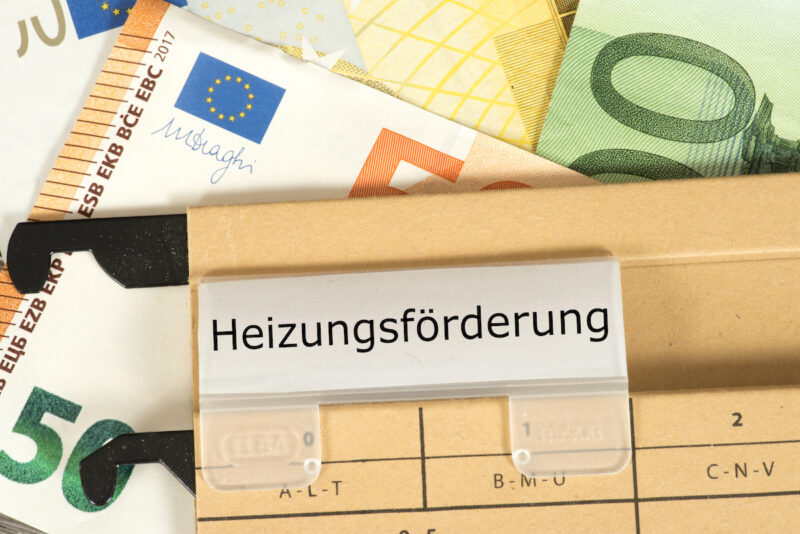 Hängemappe mit Aufschrift Heizungsförderung und Geldscheinen - Symbol für BEG.