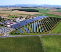 Luftaufnahme von Gewerbepark im Grünen mit Photovoltaik auf Dächern und Wiesen.