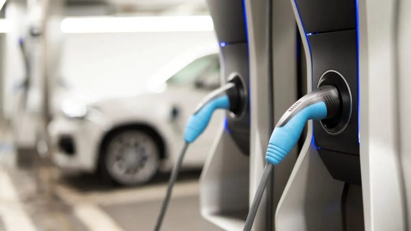 Zwei Ladesäulen aund Fahrzeuge im unscharfen Hintergrund