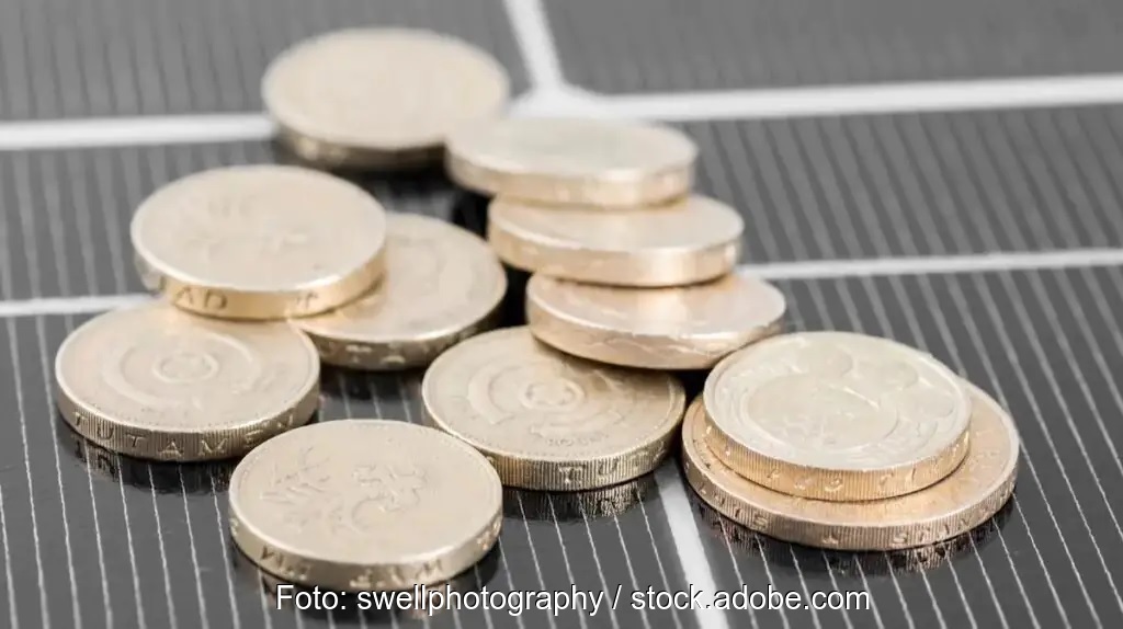 Münzen auf PV-Modul als Symbol für EEG-Konto und Strommarktreform.
