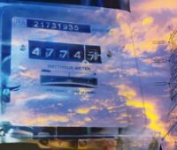 ein Himmel im Morgenrot mit Wolken spiegelt sich in Scheibe vor Stromzähler - Symbolbild für Smart Meter Rollout
