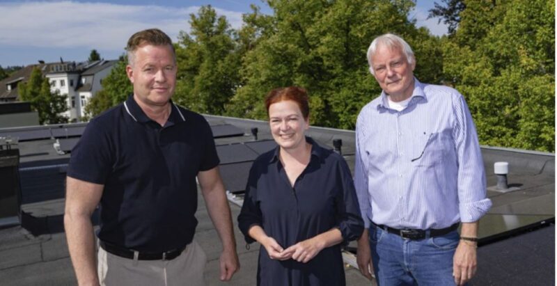 Eine Frau und zwei Männer auf einem Dach mit PV-Modulen.
