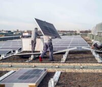 Handwerker bauen PV-Anlage aus einem Gründach