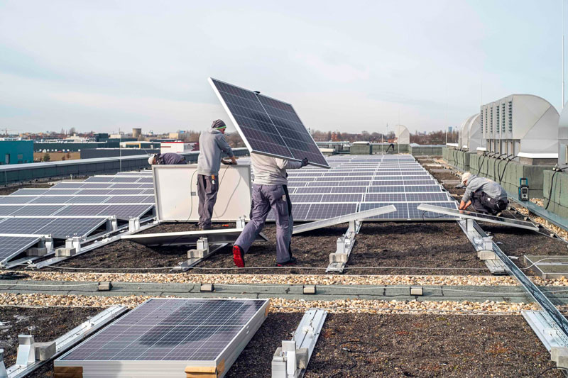 Handwerker bauen PV-Anlage aus einem Gründach