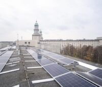 PV-Module auf einem Flachdach. Im Hintergrund Kirchtürme von Berlin.