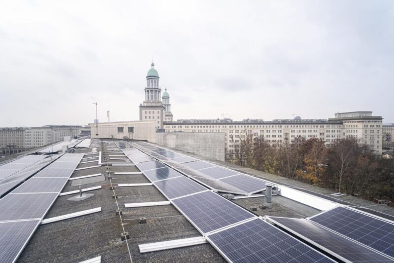 PV-Module auf einem Flachdach. Im Hintergrund Kirchtürme von Berlin.