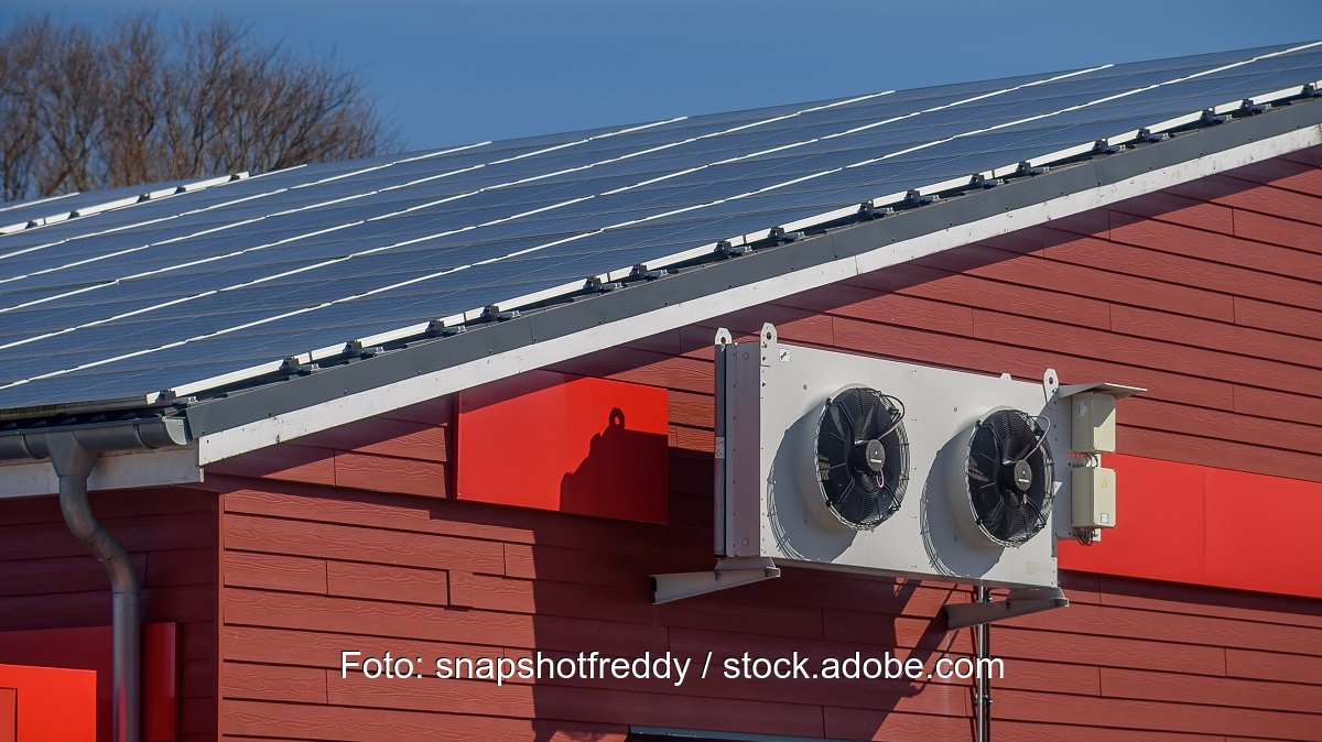 Eine Klimaanlage an einer Hauswand mit Photovoltaik auf dem Dach.