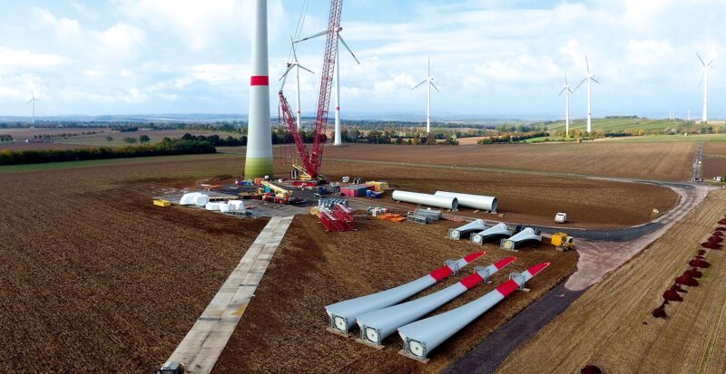 Zu sehen ist der Bau einer Windenergieanlage auf einem Acker. Windenergieanlagen in Industrie- und Gewerbegebieten sind schwierig umzusetzen.