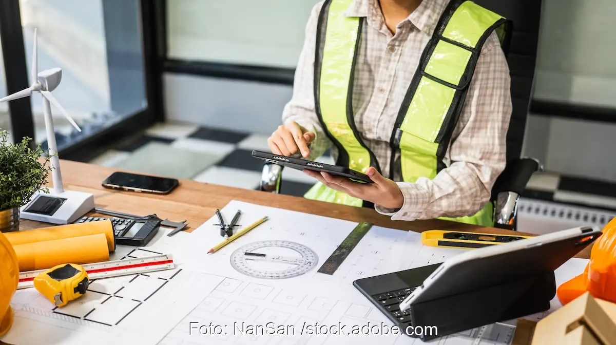 Mensch am Schreibtisch mit Windenergie-Modell und anderen Materialien, der Bundesverband Windenergie fürchtet, dass die RED-III-Teilumsetzung Genehmigungsverfahren nicht wie gewünscht beschleunigt.