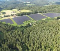 Luftbild eines PV-Parks umgeben von Wäldern.