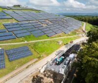 Deponieberg mit PV-Modulen und Tankstelle am Fuß des Hügels.