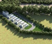 Zu sehen ist das zukünftige Speicherprojekt Batteriegroßspeicher Brietlingen aus der Vogelperspektive. Es liegt auf einer grüner Wiese umfasst von einem Weg rundherum, der von Bäumen gesäumt ist.