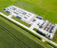 Luftbild zeigt einen großen Batteriespeicher mit mehreren Containern an einem Weg inmitten von Wiesen. Symbolbild für Flächenpooling.